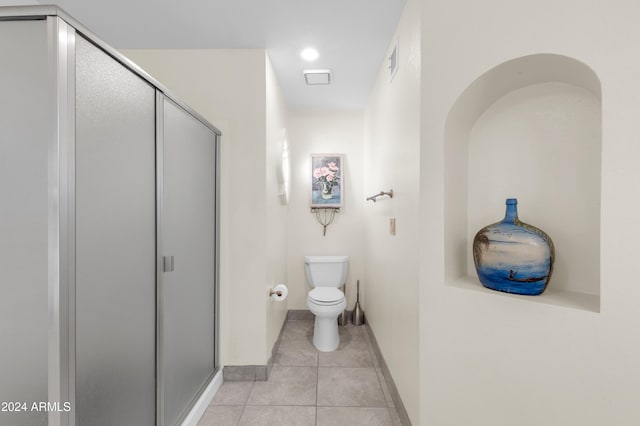 bathroom with tile patterned flooring, an enclosed shower, and toilet