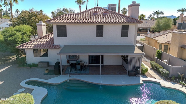 rear view of property with central air condition unit, a patio, and a fenced in pool