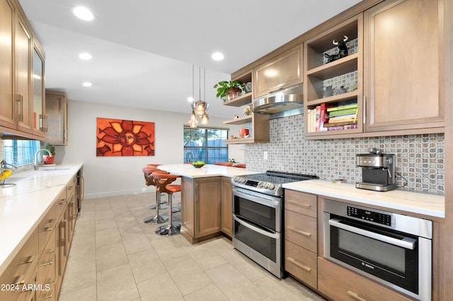 kitchen with tasteful backsplash, stainless steel appliances, pendant lighting, a breakfast bar area, and light tile patterned flooring