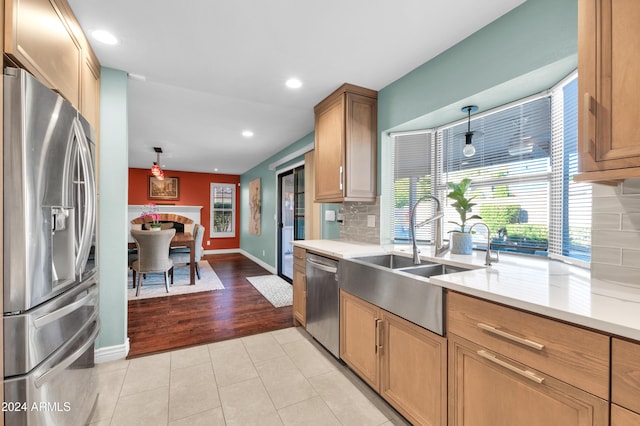 kitchen featuring pendant lighting, light hardwood / wood-style floors, sink, and appliances with stainless steel finishes