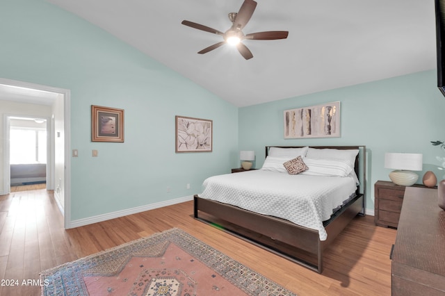 bedroom with ceiling fan, light hardwood / wood-style floors, and vaulted ceiling