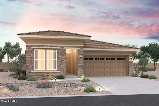 prairie-style home with stone siding, stucco siding, driveway, and a garage