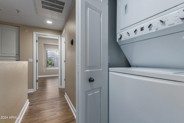 laundry room with stacked washer and clothes dryer and hardwood / wood-style flooring