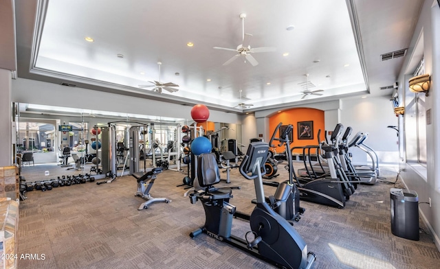 workout area with a raised ceiling, ceiling fan, and carpet floors