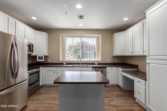 kitchen with sink, appliances with stainless steel finishes, a center island, and dark wood-type flooring