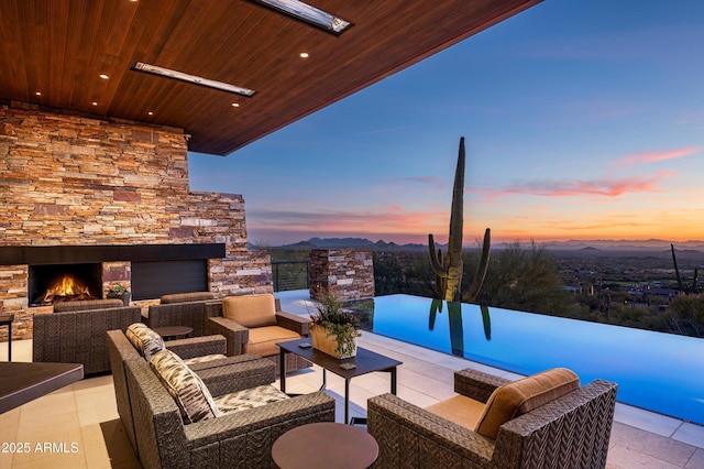 patio terrace at dusk with an outdoor living space with a fireplace and a mountain view