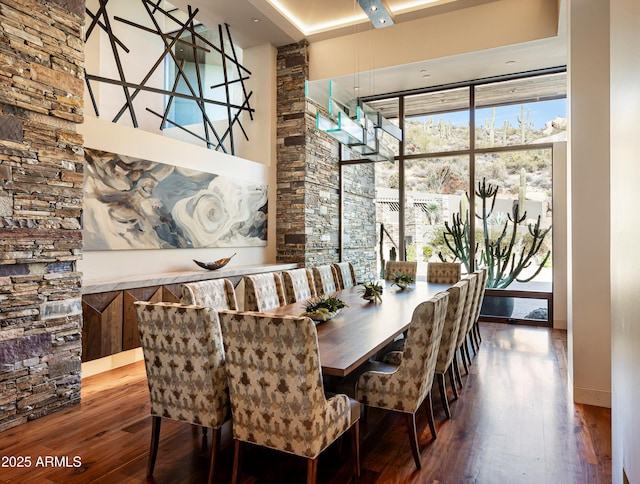 dining area featuring a towering ceiling and wood-type flooring