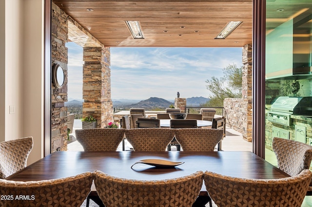 dining space with a mountain view, plenty of natural light, and wooden ceiling