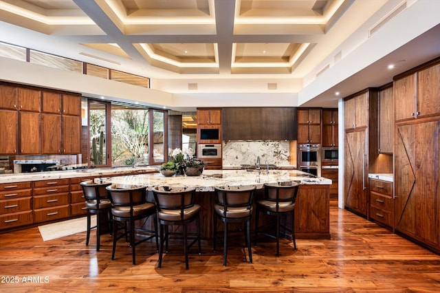 kitchen with double oven, a large island, light stone countertops, and a high ceiling