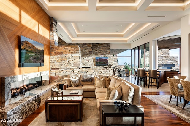 living room featuring a stone fireplace, wooden walls, and dark wood-type flooring