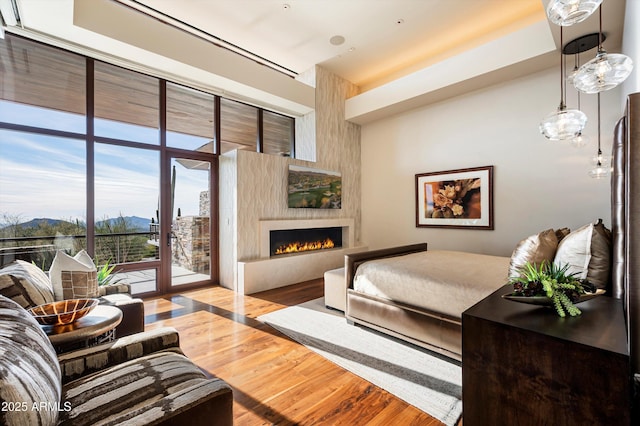 bedroom with access to outside, a fireplace, and light hardwood / wood-style flooring