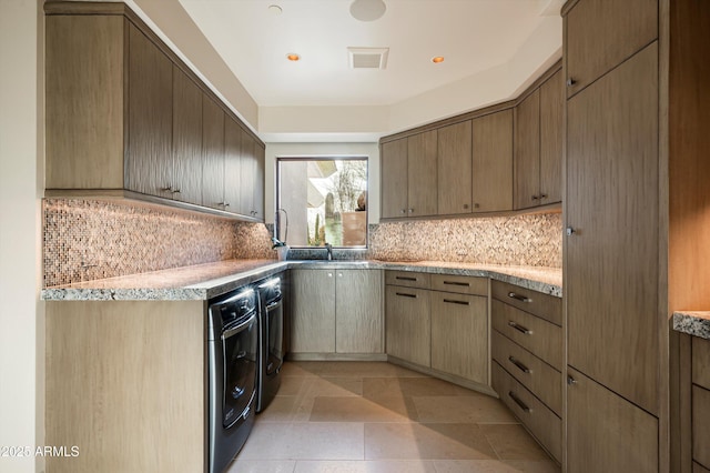 kitchen featuring light stone countertops, tasteful backsplash, sink, washing machine and dryer, and light tile patterned flooring