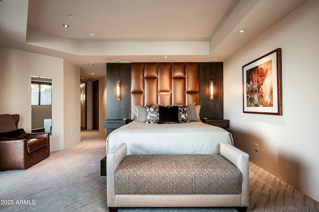 bedroom with a raised ceiling and light colored carpet