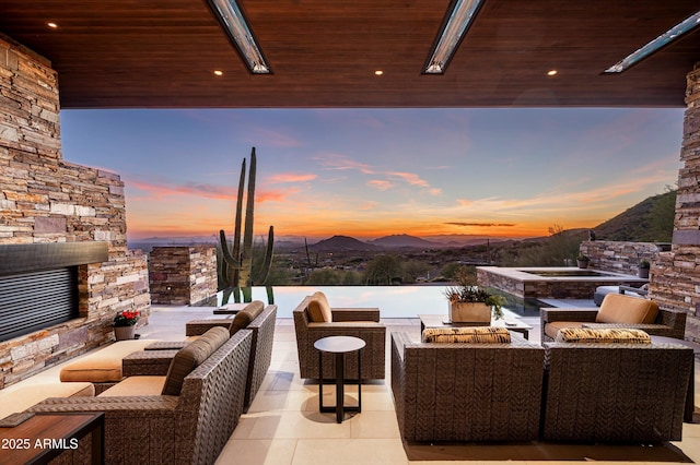 patio terrace at dusk featuring a mountain view and an outdoor hangout area