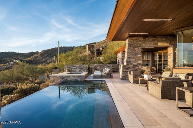 view of swimming pool with outdoor lounge area, a mountain view, and a patio area