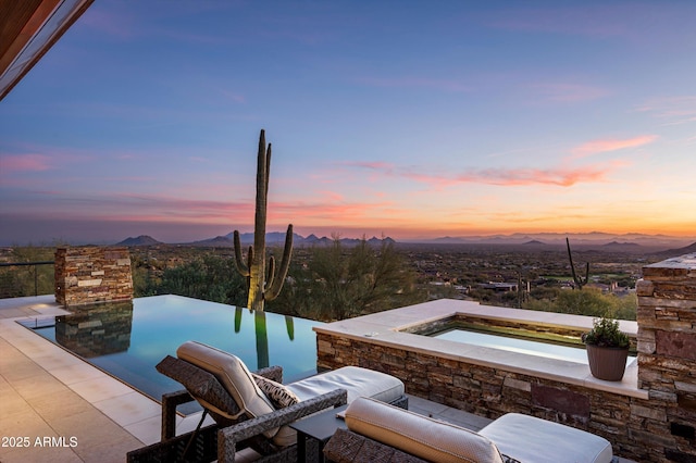 patio terrace at dusk featuring a mountain view and an in ground hot tub