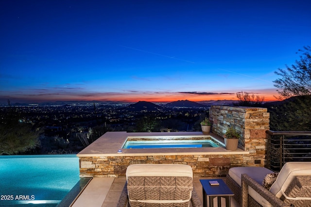 pool at dusk with an in ground hot tub and a mountain view