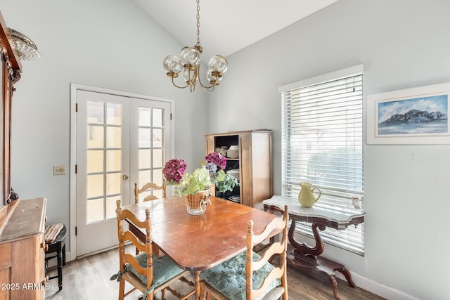 dining room featuring vaulted ceiling, light hardwood / wood-style flooring, an inviting chandelier, and french doors