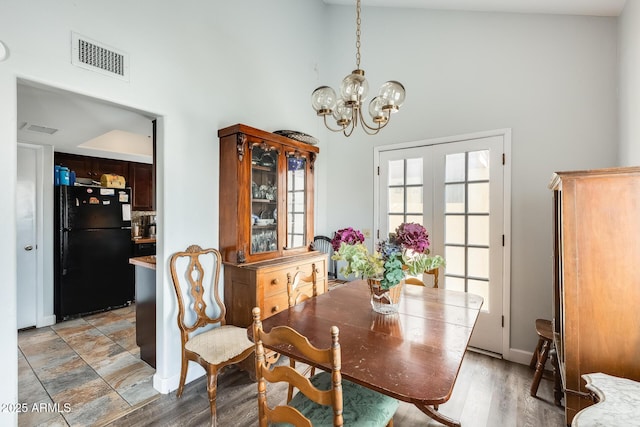 dining room with hardwood / wood-style flooring, a towering ceiling, and a notable chandelier