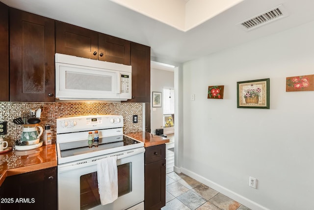 kitchen with dark brown cabinetry, light tile patterned floors, backsplash, and white appliances