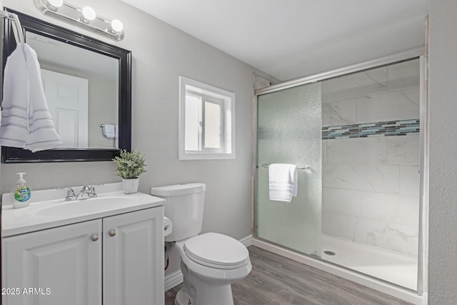 bathroom with vanity, toilet, a shower with door, and wood-type flooring