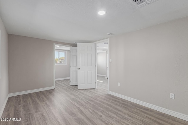 unfurnished room featuring light hardwood / wood-style floors and a textured ceiling