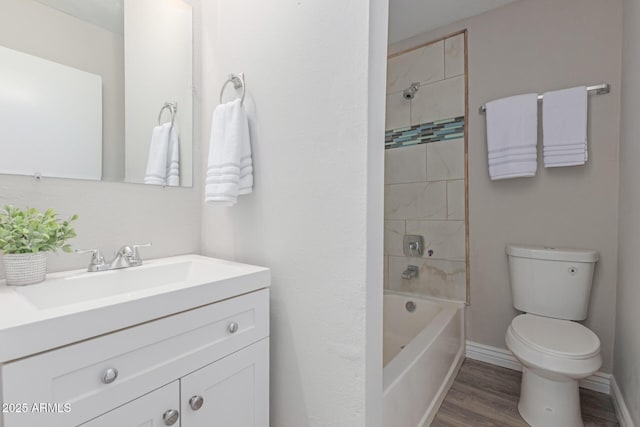 full bathroom with wood-type flooring, tiled shower / bath, vanity, and toilet