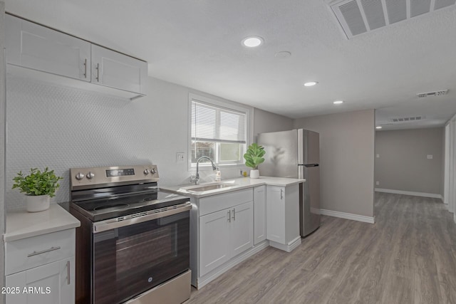 kitchen with sink, light hardwood / wood-style flooring, appliances with stainless steel finishes, white cabinetry, and a textured ceiling