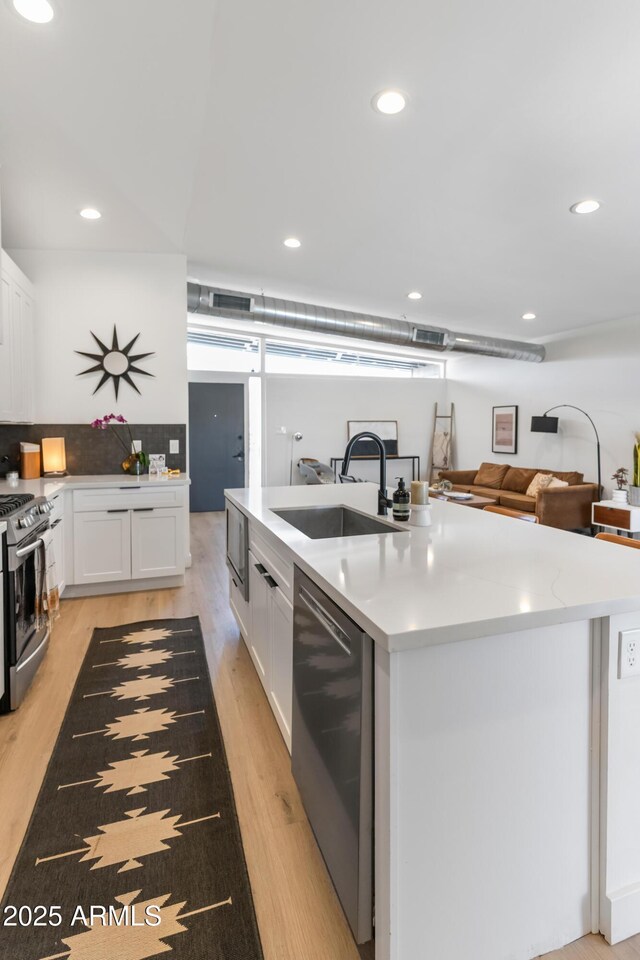 1212 E Indianola Ave, Phoenix, AZ 85014 - kitchen with a sink, an island with sink, stainless steel appliances, light wood finished floors, and white cabinets