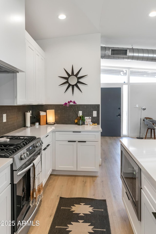 1212 E Indianola Ave, Phoenix, AZ 85014 - kitchen with tasteful backsplash, white cabinetry, light countertops, appliances with stainless steel finishes, and visible vents