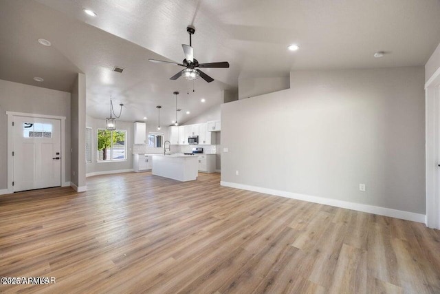 780 E Cobble Ln, Taylor, AZ 85939 - unfurnished living room with a ceiling fan, vaulted ceiling, a sink, baseboards, and light wood-style floors