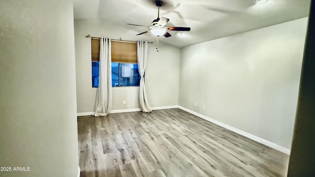 empty room featuring baseboards, wood finished floors, and a ceiling fan