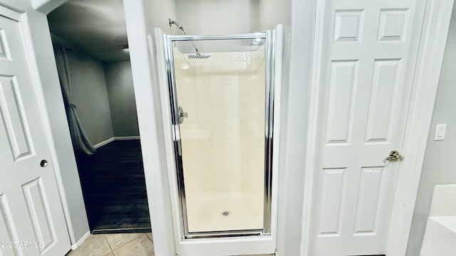 bathroom with tile patterned floors, baseboards, and a stall shower