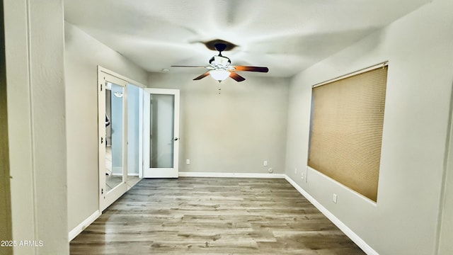 empty room with a ceiling fan, baseboards, and wood finished floors