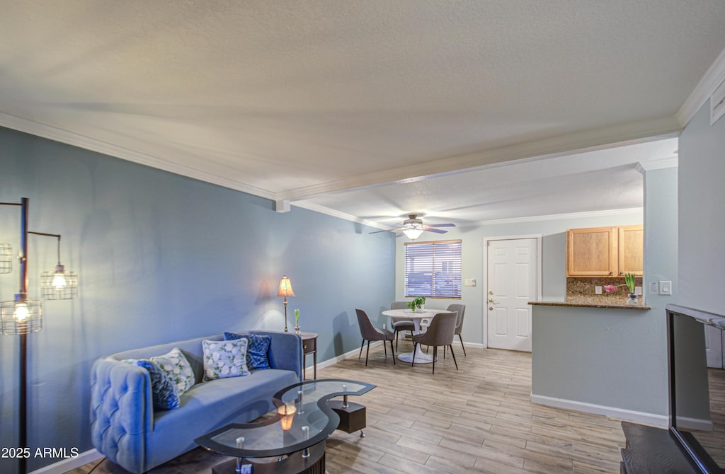 living room featuring light wood finished floors, baseboards, ceiling fan, and ornamental molding