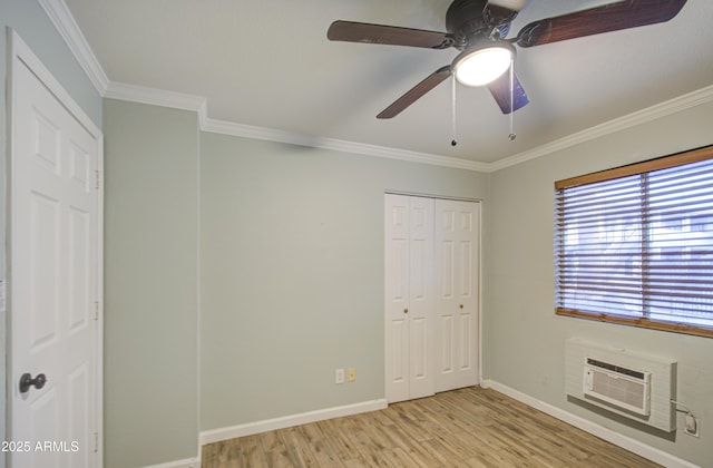 unfurnished bedroom featuring an AC wall unit, light wood-style flooring, crown molding, baseboards, and ceiling fan