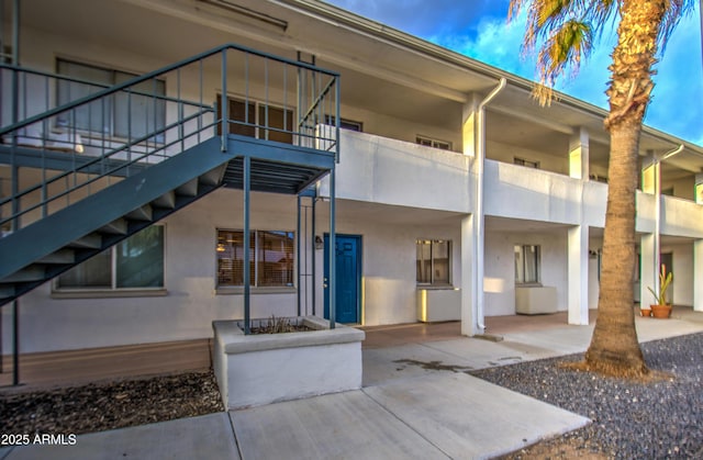 back of house featuring stairway and stucco siding