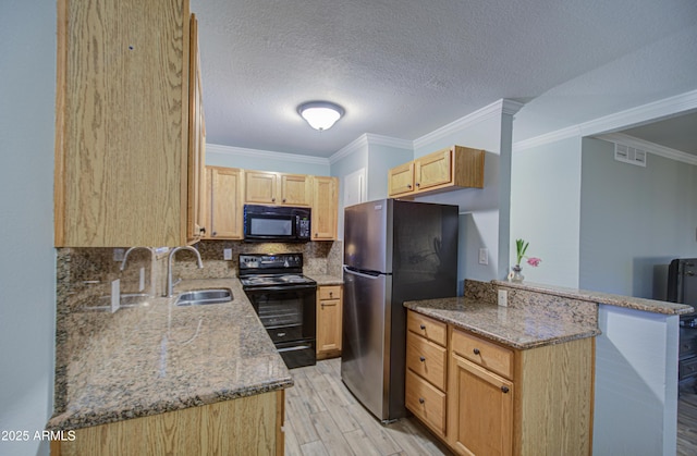 kitchen with visible vents, black appliances, light brown cabinetry, a sink, and a peninsula