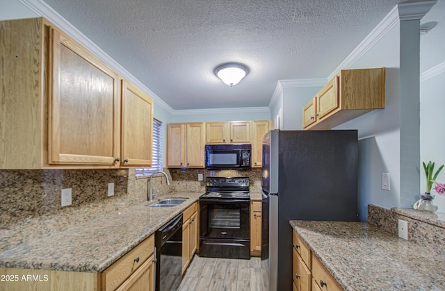 kitchen featuring light stone counters, ornamental molding, decorative backsplash, black appliances, and a sink