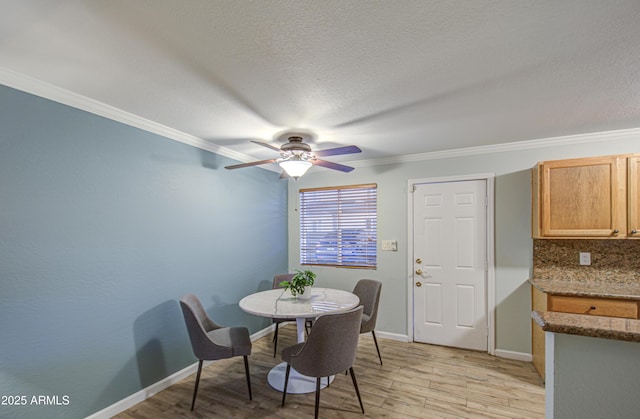 dining space with light wood finished floors, crown molding, baseboards, a textured ceiling, and a ceiling fan