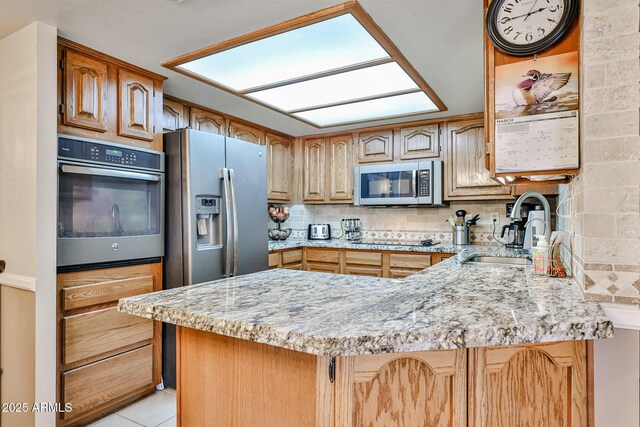 17404 N 99th Ave Unit 318, Sun City, AZ 85373 - kitchen with a peninsula, backsplash, light stone countertops, stainless steel appliances, and a sink
