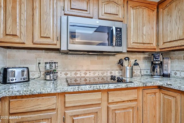 17404 N 99th Ave Unit 318, Sun City, AZ 85373 - kitchen featuring decorative backsplash, black electric stovetop, and stainless steel microwave