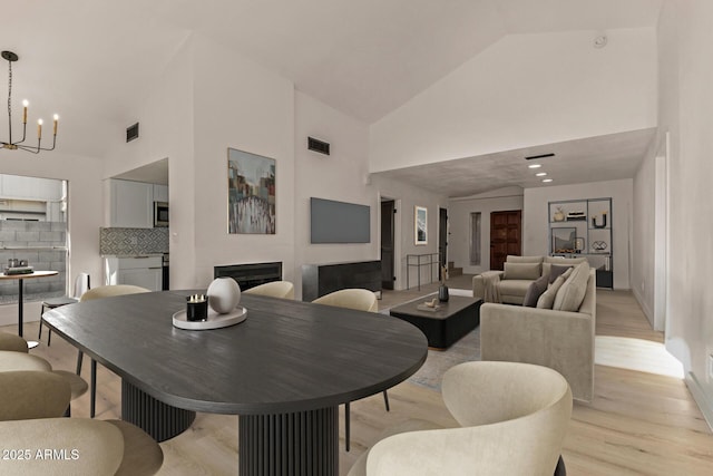 1610 N Apache Dr, Chandler, AZ 85224 - dining area with high vaulted ceiling, a chandelier, light wood-style floors, and a fireplace