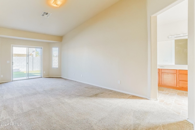 carpeted spare room featuring vaulted ceiling