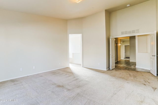 carpeted spare room featuring a high ceiling