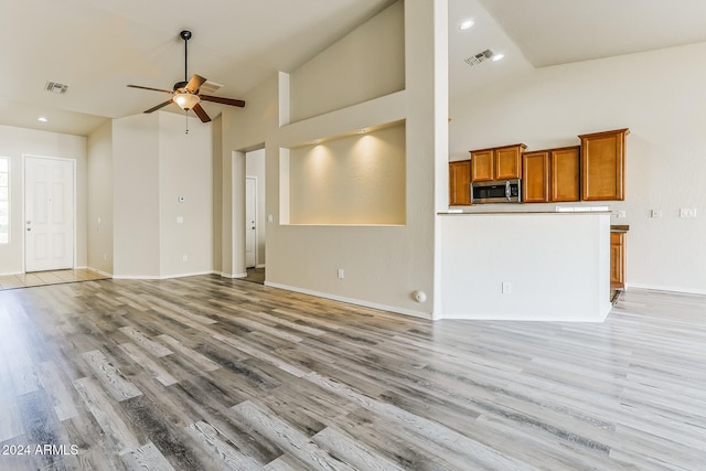 unfurnished living room featuring light hardwood / wood-style floors, high vaulted ceiling, and ceiling fan