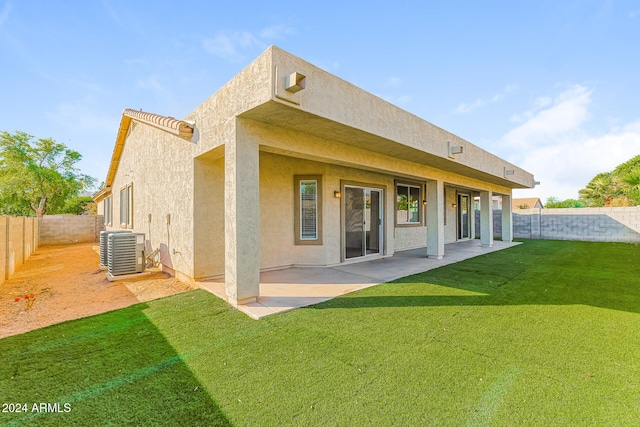 rear view of house featuring central AC unit, a yard, and a patio