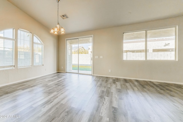 empty room with wood-type flooring and a notable chandelier