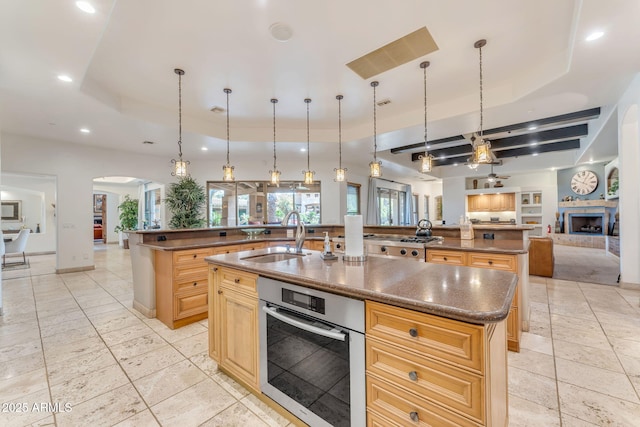 kitchen with a large island, sink, oven, and a raised ceiling