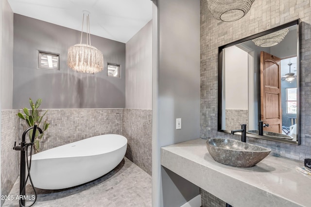 bathroom with sink, a notable chandelier, and a tub to relax in